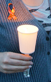 Carrying a lit candle and wearing a homemade red ribbon pin ath the Candle Parade