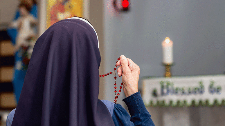 Nun holding rosary up in church